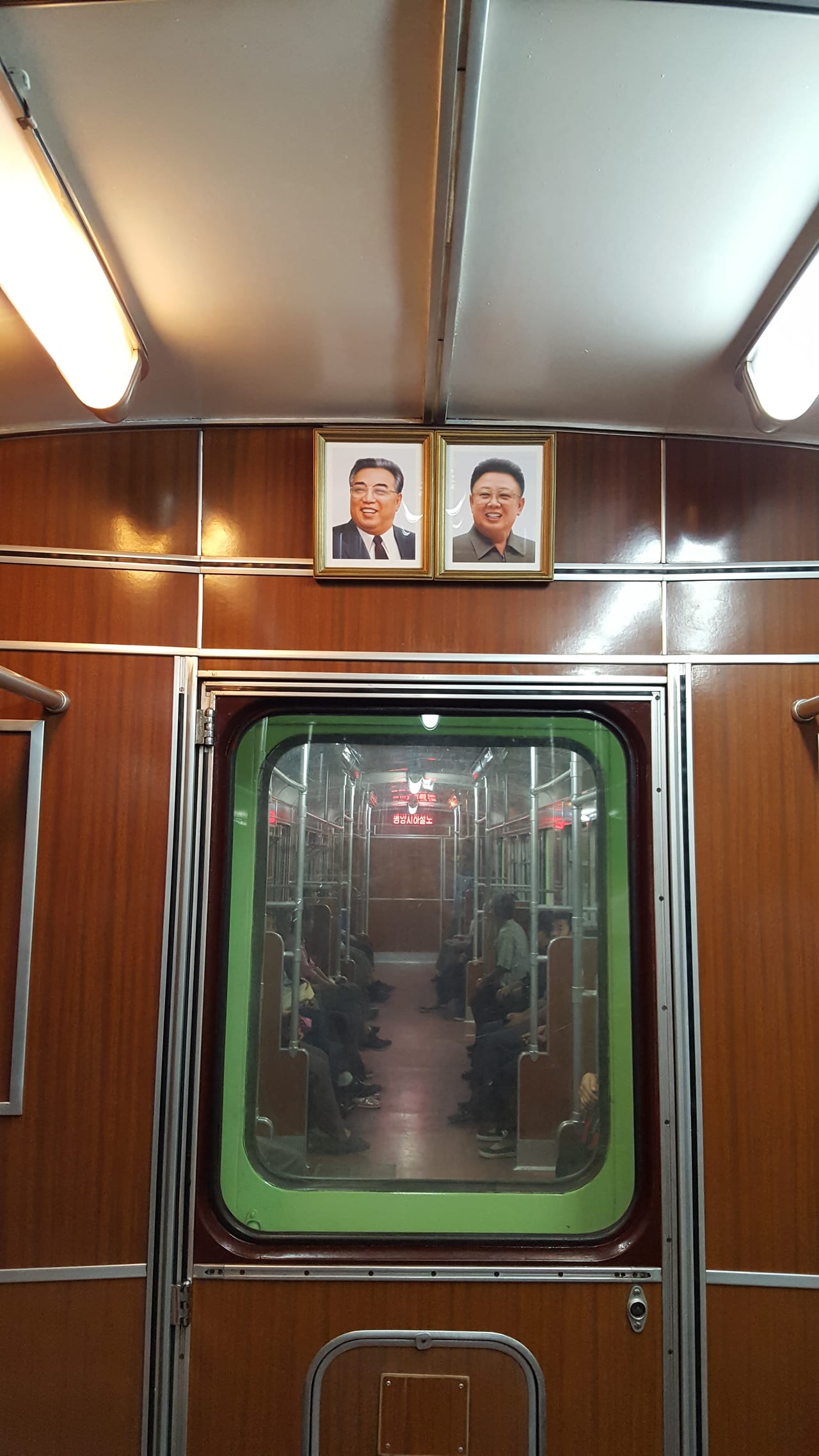 Looking through the connected metro cars, with the framed supreme leaders in full view.