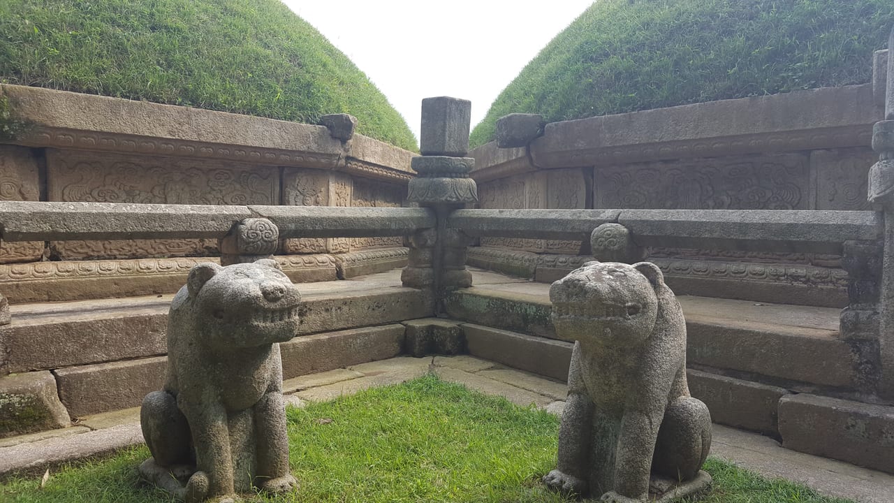 Small big-cat statues at the base of the tomb.