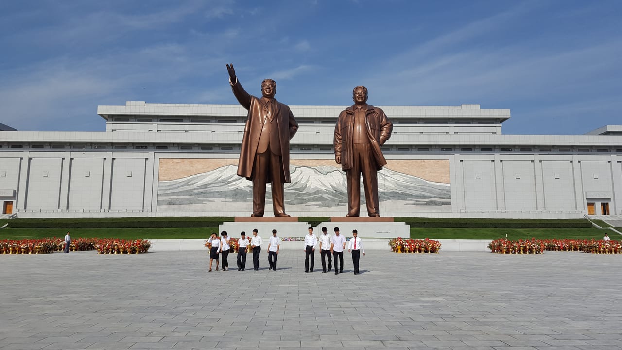 A young North Korean group honoring the statues with flowers at Mansudae Grand Monument.