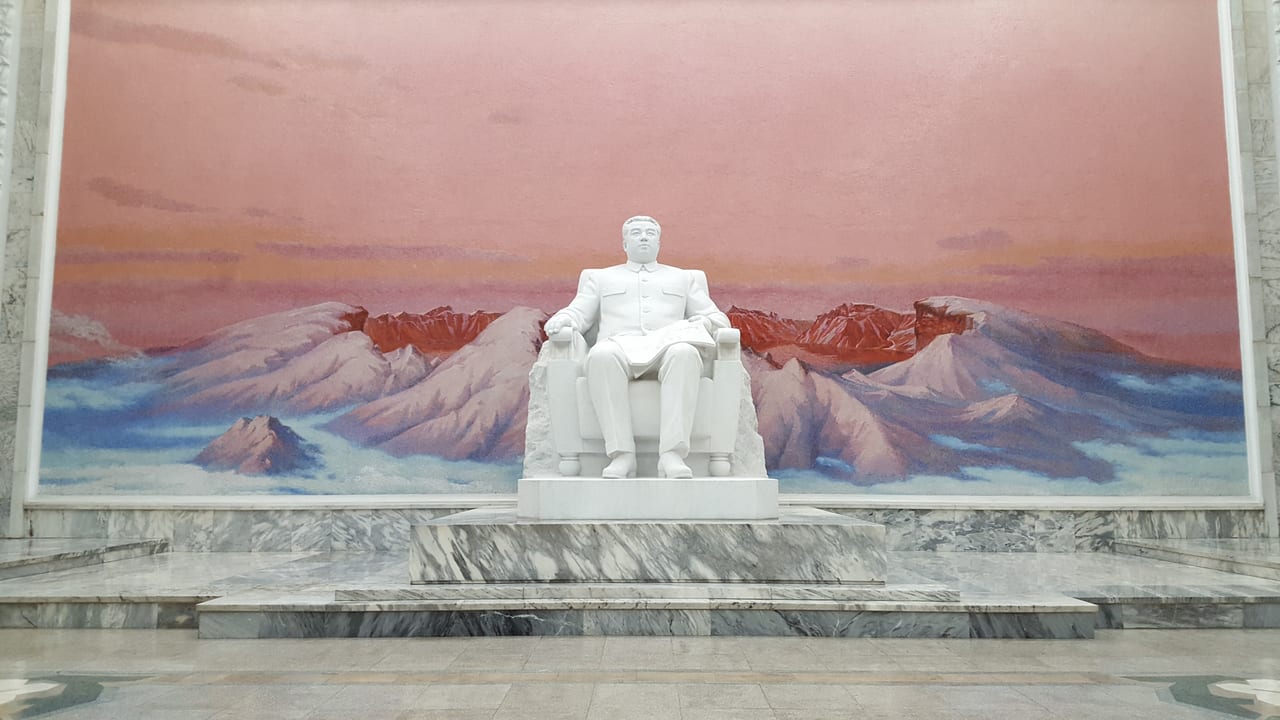A large marble statue of Kim Il Sung seated in front of a larger Mount Paektu mural at the entrance of the Grand People's Study House. Mount Paektu is a cultural icon to the North Koreans as a most holy landscape. Claimed to be the birthplace of Kim Jong Il, although Soviet records document otherwise.